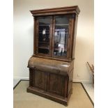 A Victorian mahogany cylinder bureau bookcase, the moulded cornice above two glazed and barred doors