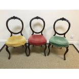 A set of three Victorian mahogany balloon back dining chairs with red, green and yellow velvet