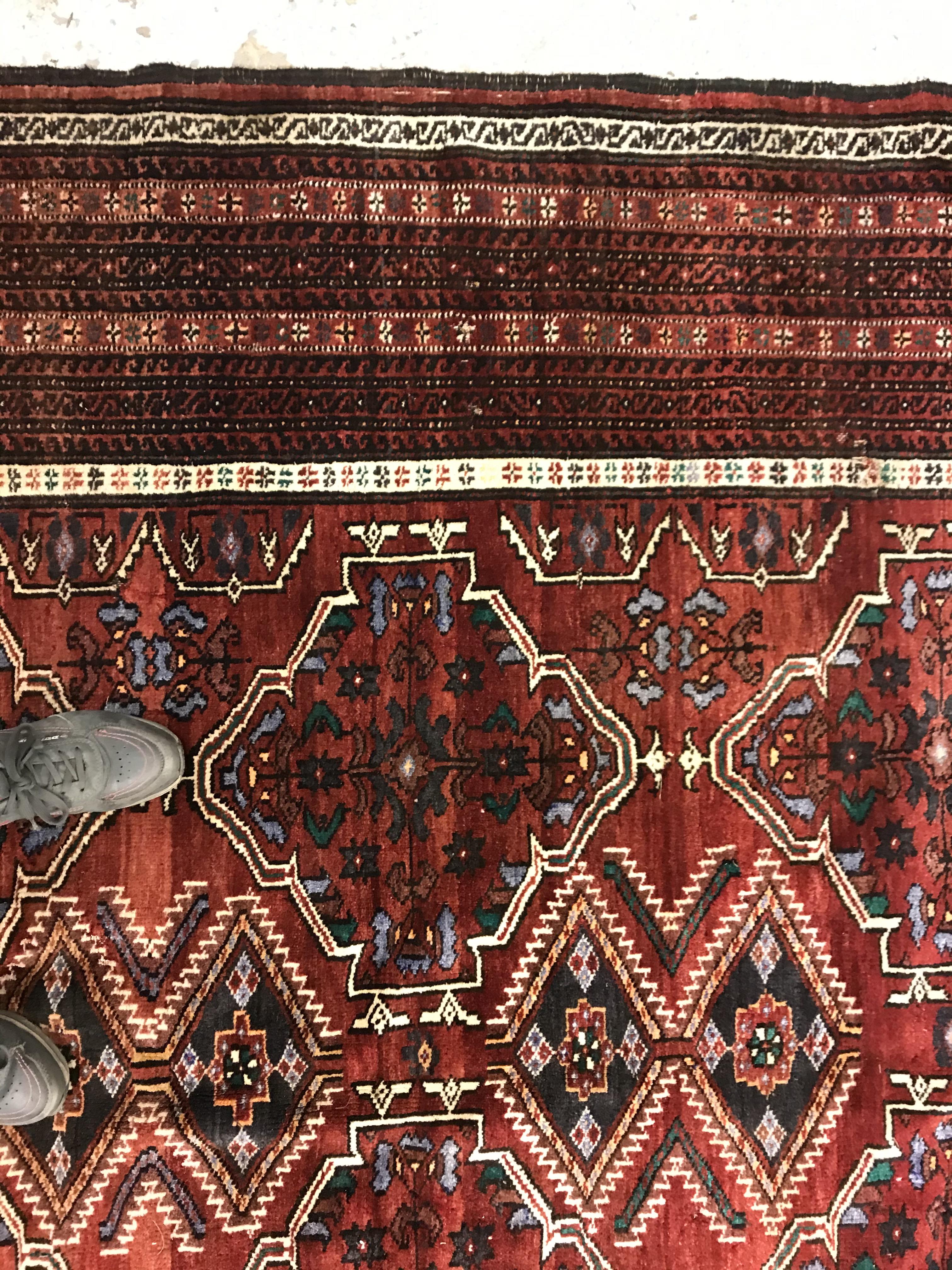 A Caucasian carpet, the central panel set with repeating medallion decoration on a blood red - Image 7 of 15