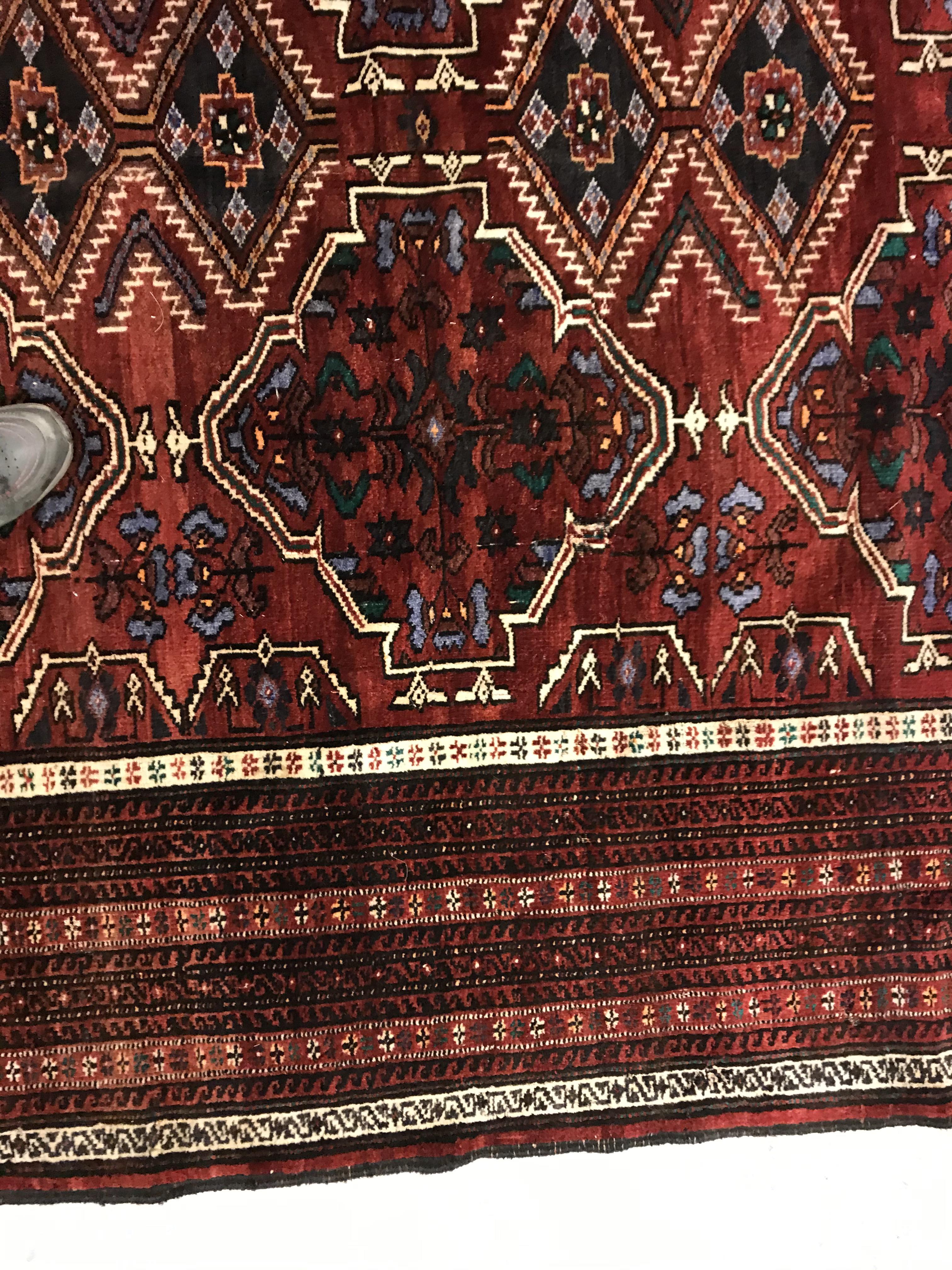 A Caucasian carpet, the central panel set with repeating medallion decoration on a blood red - Image 6 of 15