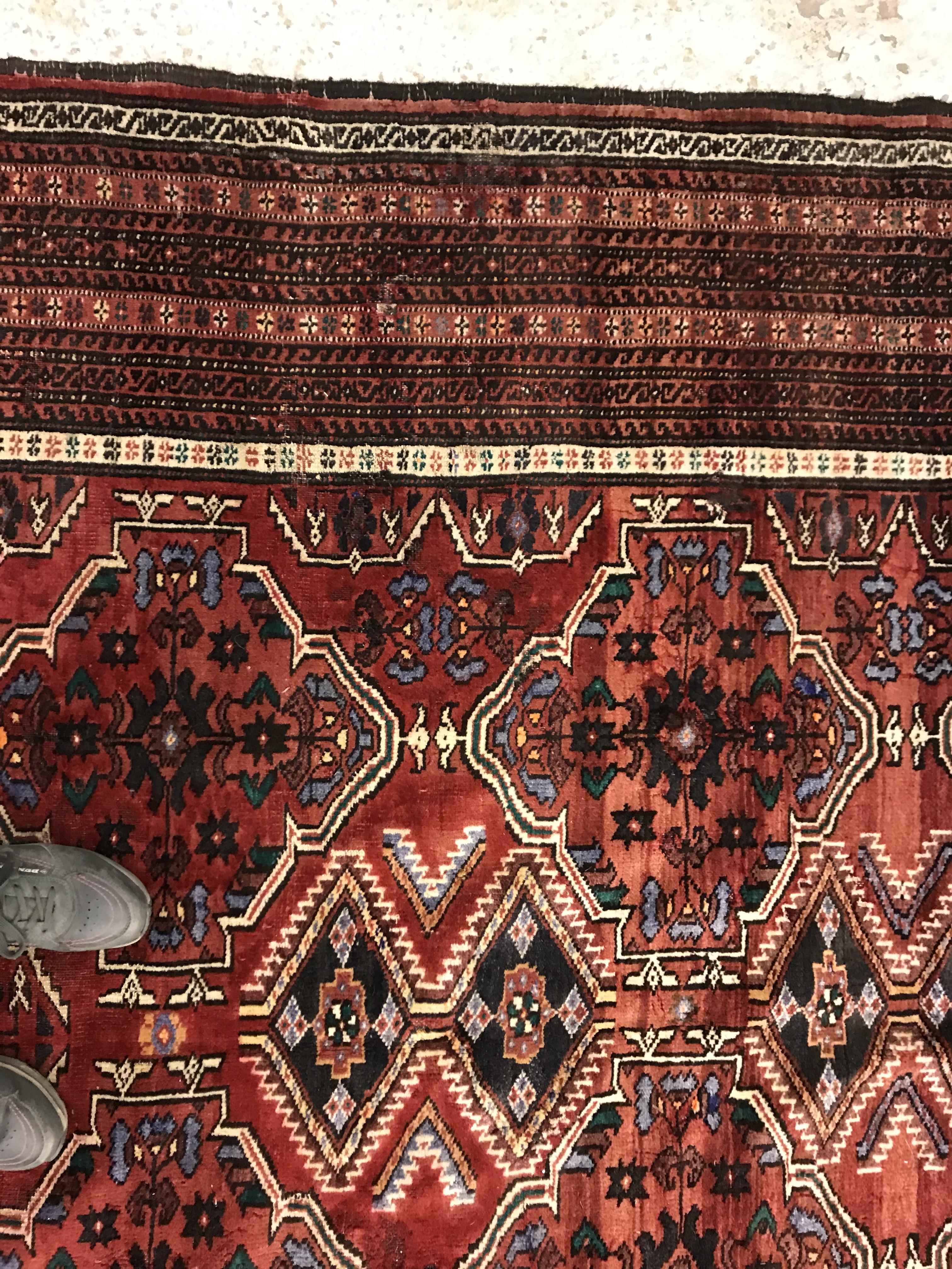 A Caucasian carpet, the central panel set with repeating medallion decoration on a blood red - Image 4 of 15