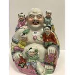 A 20th Century Chinese figure of a seated smiling Buddha with five children, 32.5 cm high