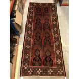 A Persian carpet, the central panel set with repeating arch decoration on a black and red ground,