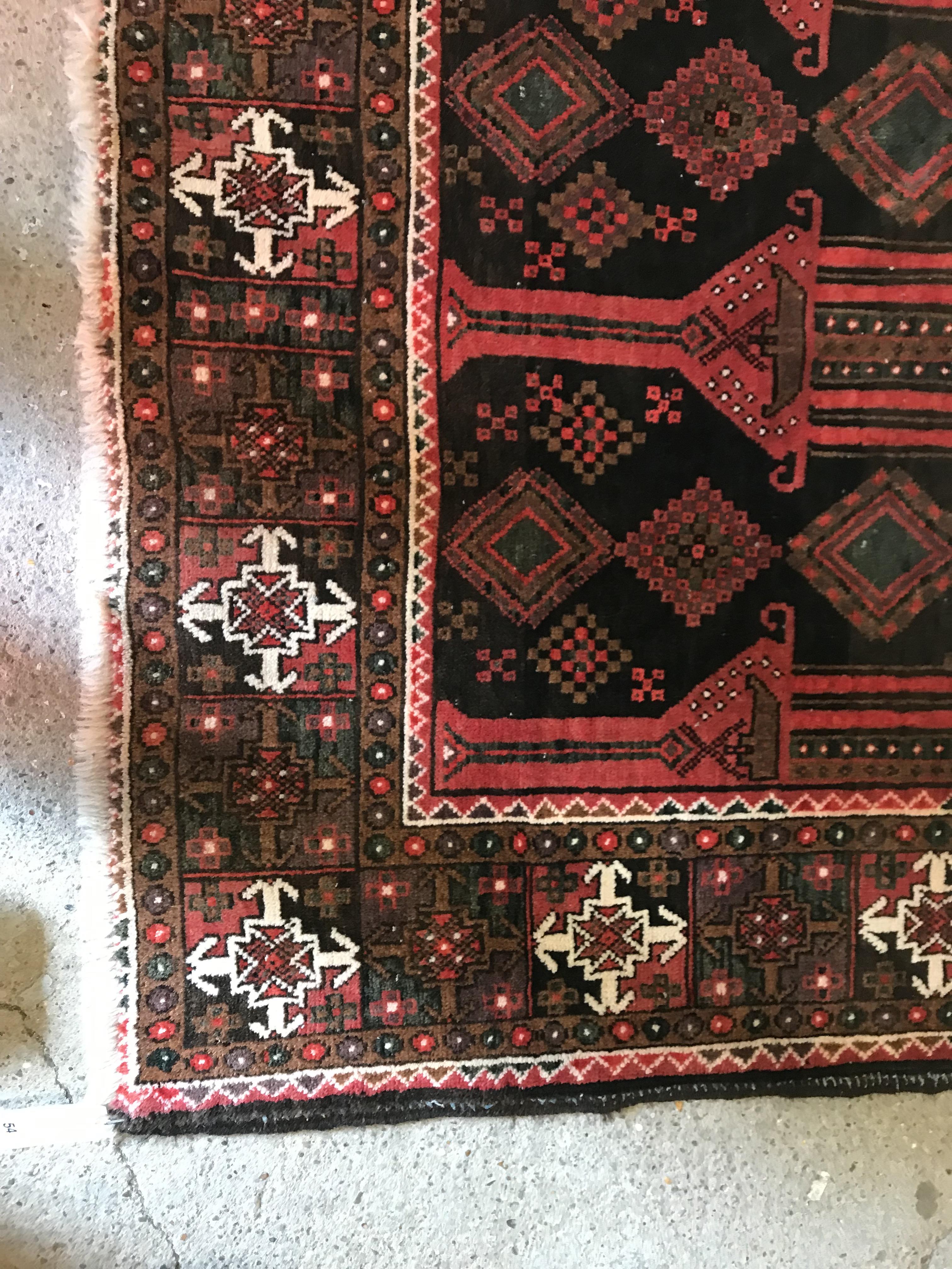 A Persian carpet, the central panel set with repeating arch decoration on a black and red ground, - Image 3 of 17