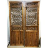 A modern Chinese stained pine and pierced two fold screen with geometric and foliate decoration over