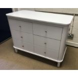 A modern white painted MDF chest of six drawers with brown leather loop handles, flanked by pull-out