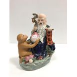 A 20th Century porcelain figure group as a Taoist sage with staff and scroll being presented a large