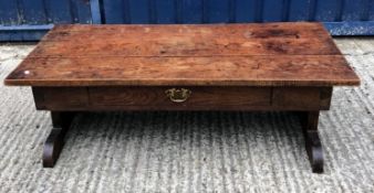 An oak coffee table, the three plank top above a frieze drawer on end pillar supports to splayed