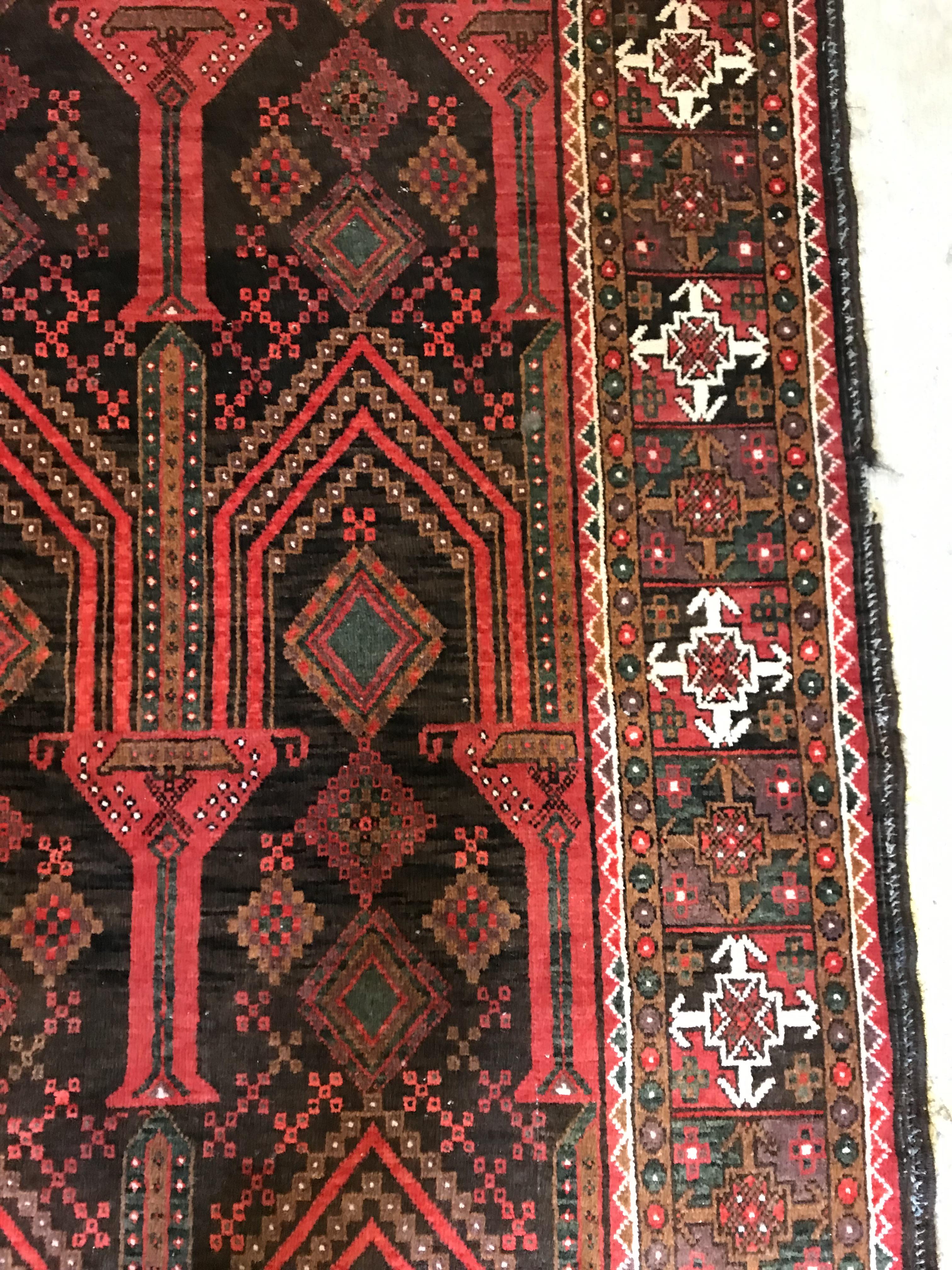 A Persian carpet, the central panel set with repeating arch decoration on a black and red ground, - Image 7 of 17