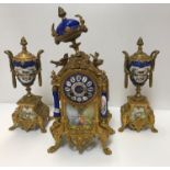 A French gilt metal clock garniture with Sèvres style bleu royale porcelain decoration, the movement