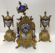 A French gilt metal clock garniture with Sèvres style bleu royale porcelain decoration, the movement