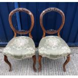 A set of six Victorian walnut balloon back dining chairs with upholstered seats on turned and fluted
