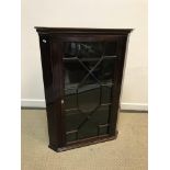 An early 19th Century mahogany hanging corner cabinet, the moulded cornice with lozenge inlaid