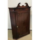 An early 19th Century mahogany and inlaid hanging corner cupboard with broken arch pediment over a
