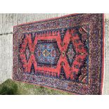 A Caucasian carpet, the central panel set with stylised flower head decorated medallion on a red and