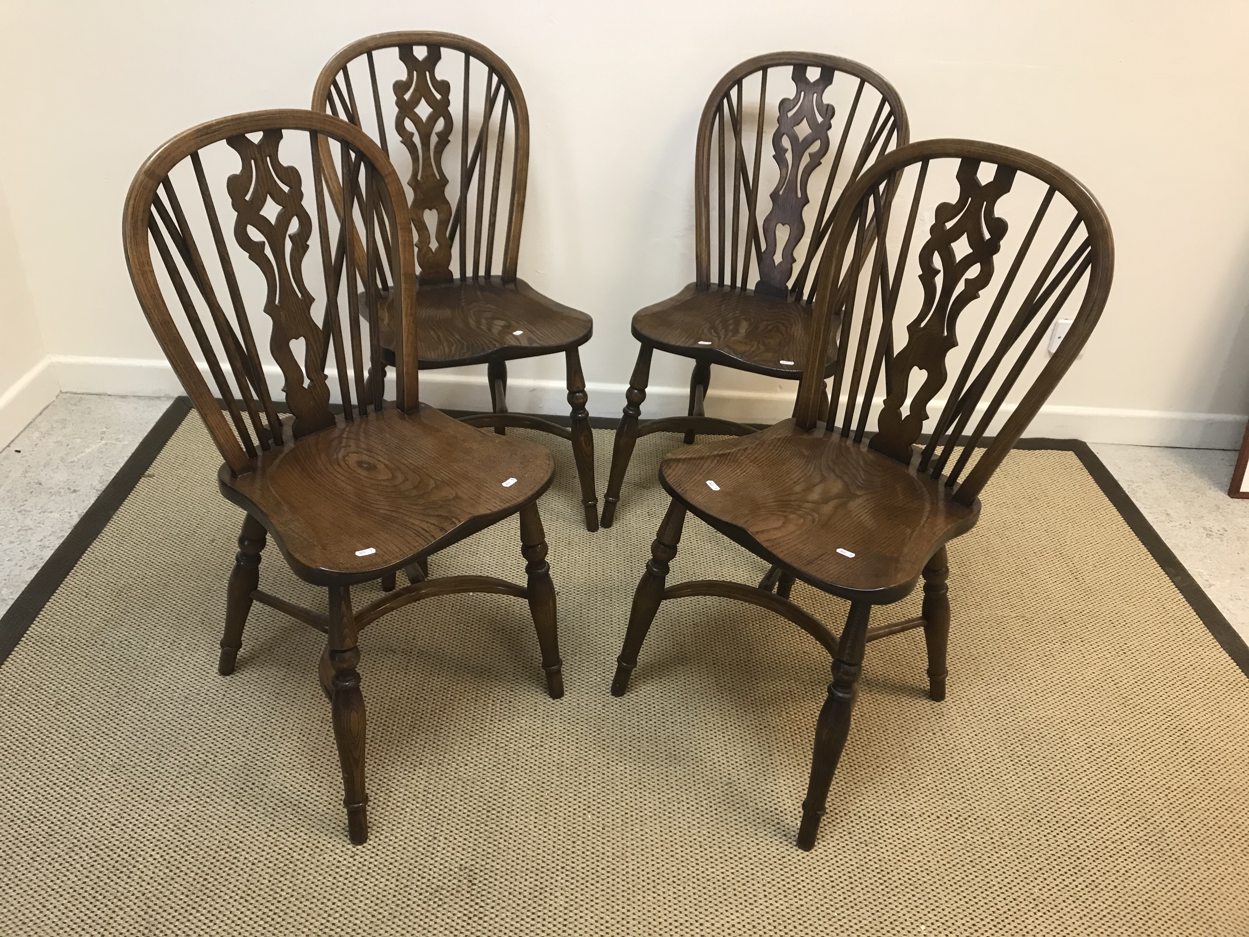 A set of four ash and elm stick back chairs in the 19th Century style, the shaped seats on turned