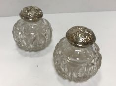 A pair of cut glass silver-mounted dressing table scent bottles, the covers with classical style