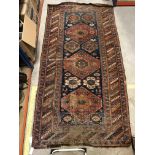 A Caucasian rug, the central panel set with repeating medallions on a blue ground with stylised