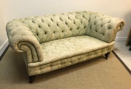 A late Victorian buttoned upholstered scroll arm chesterfield sofa on turned front legs to casters