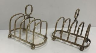 A pair of George VI silver four section toast racks of rounded rectangular form, raised on four ball