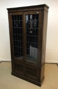 An early 20th Century oak bookcase with leaded glazed doors enclosing adjustable shelving over two