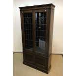 An early 20th Century oak bookcase with leaded glazed doors enclosing adjustable shelving over two