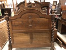 A French walnut double bedstead in the Renaissance manner with carved urn finials and shaped