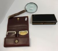An Asprey black leather cigarette box with yellow metal mounts, a Cartier burgundy leather playing