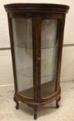 A modern stained beech framed demi lune vitrine in the French taste with carved decoration, the