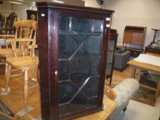 An early 19th Century mahogany hanging corner cabinet, the moulded cornice with lozenge inlaid