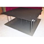 A Ligne Roset two tier coffee/book table, the ebonised top with chamfered edge raised on thirteen
