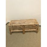 An Oliver Bonas canework two tier occasional table with arched side decoration 105.5 cm x 38 cm x
