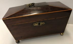 A Regency mahogany and box wood strung sarcophagus shaped tea caddy raised on brass ball feet, the