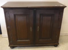 An oak two door side cabinet in the early 18th Century taste with two fielded panel doors raised