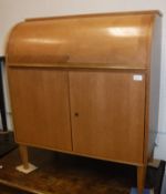 A mid-20th Century teak cylinder top bureau with basic fitted interior over two cupboard doors