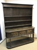 A 19th Century oak dresser, the boarded three tier plate rack over three fielded panel drawers on