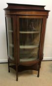 An Edwardian mahogany and satinwood banded display cabinet of demi lune form, the shallow raised