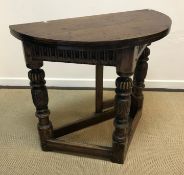 An oak Credence type side table in the 17th Century manner, the fold over top above a carved