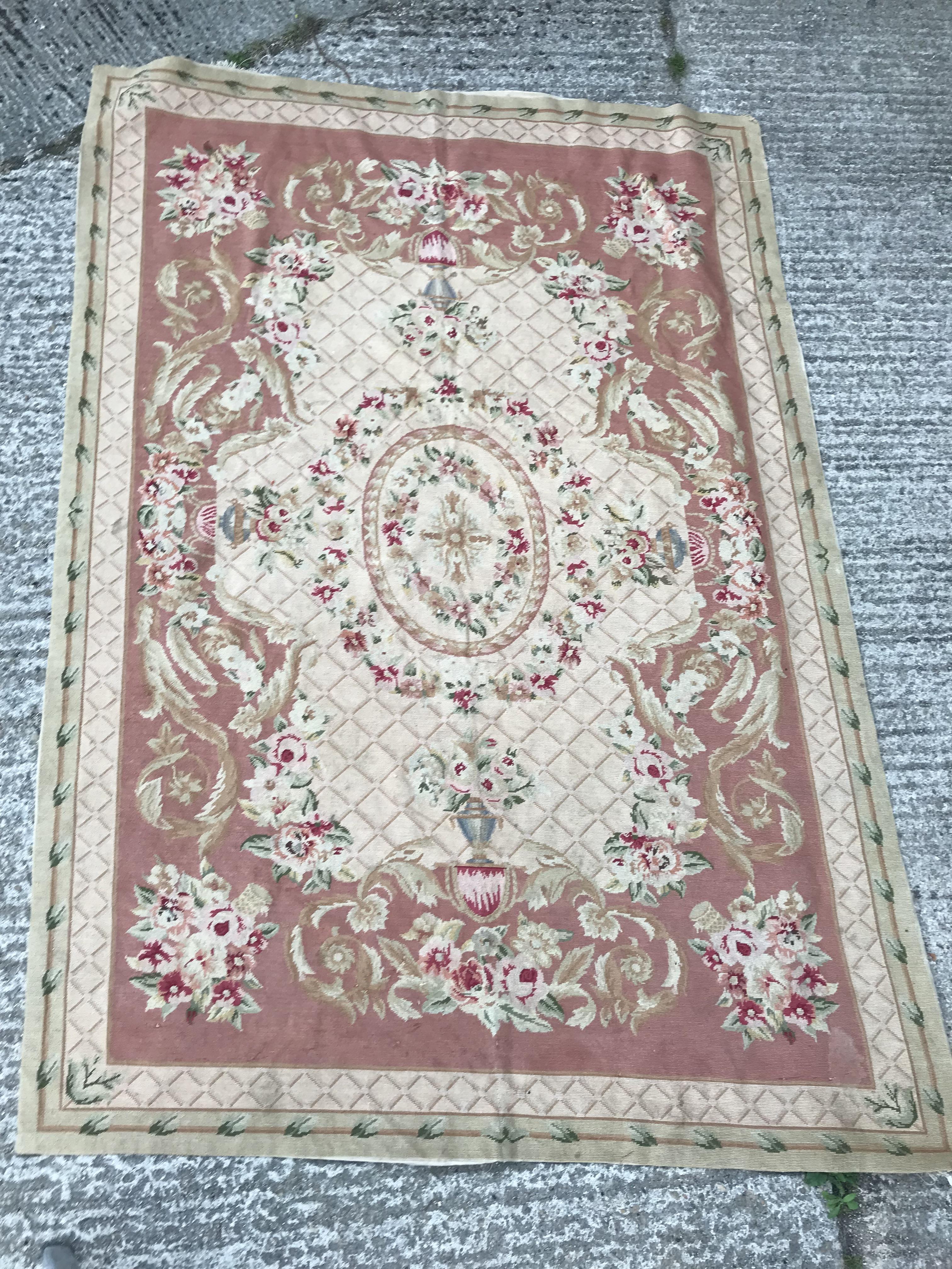 An Aubusson style rug, the central panel set with a floral decorated medallion on pale pink and dark