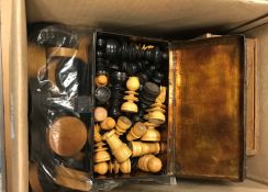 A box containing various games pieces including three chess sets, bag of draughts pieces and bag