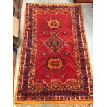 A Caucasian rug, the central panel set with three medallions on an orange and cream geometric