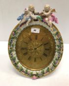 A Meissen porcelain framed oval easel backed clock decorated with floral sprays and cherubs, the