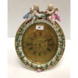 A Meissen porcelain framed oval easel backed clock decorated with floral sprays and cherubs, the