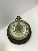 A Victorian Goliath pocket watch on a velvet covered stand, the porcelain chapter ring with Arabic