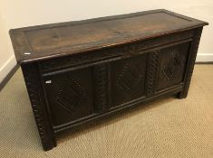 A circa 1700 oak coffer, the panelled top over a foliate carved frieze and three lozenge carved