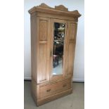 An Edwardian pine wardrobe, the mirrored single door above single drawer on plinth base, 101 cm wide