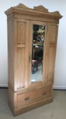 An Edwardian pine wardrobe, the mirrored single door above single drawer on plinth base, 101 cm wide