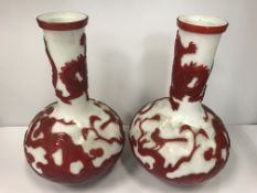 A pair of Peking glass vases of onion form in red and white with blossom, tiger and dragon