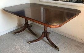 A Georgian style mahogany and cross-banded rectangular dining table on twin pillar supports, 100