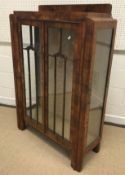 A 1930's Art Deco style walnut display cabinet with two doors enclosing glass shelving, 88 cm wide x